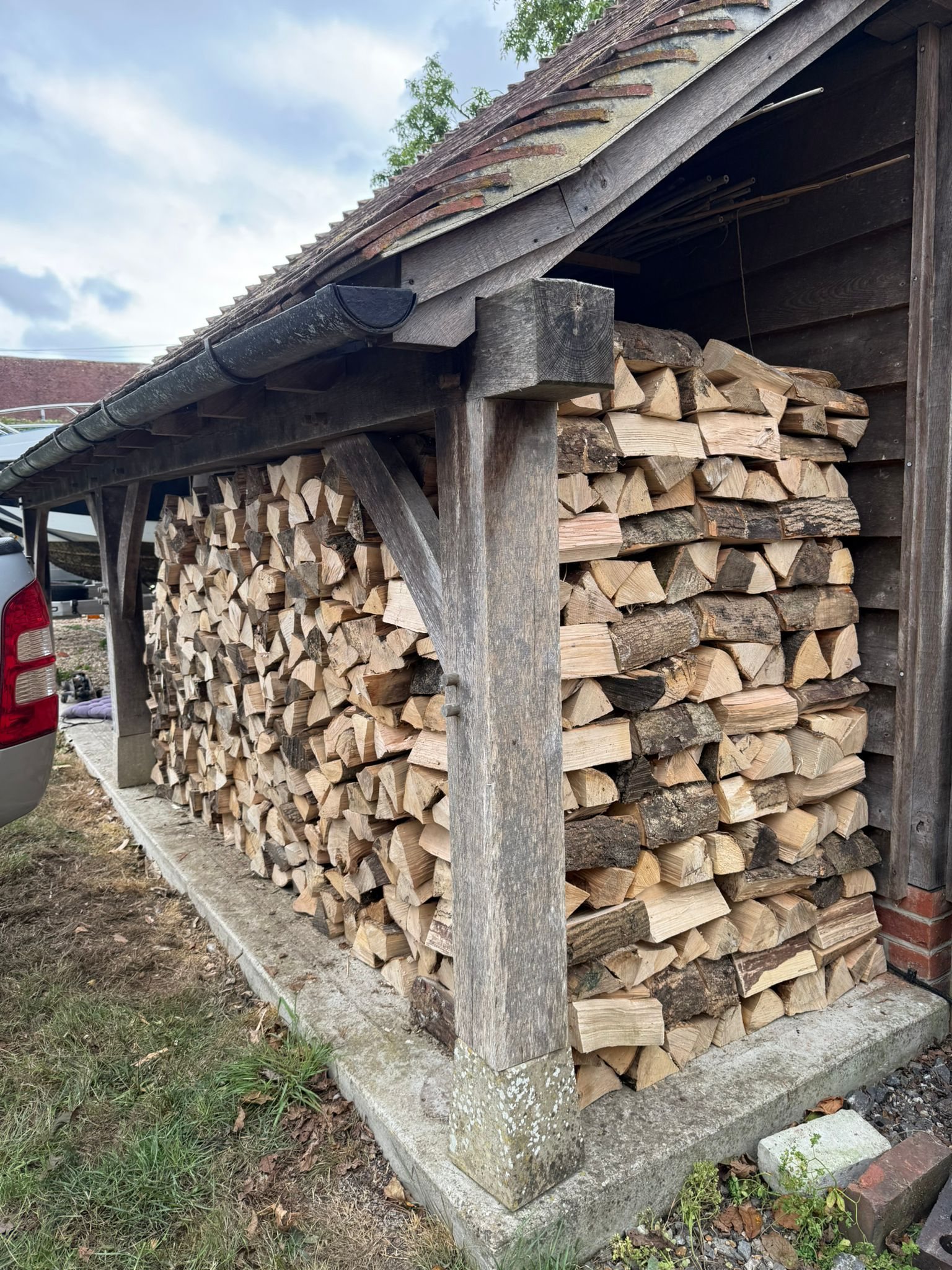 Seasoned split firewood stacked beneath an open-sided roof